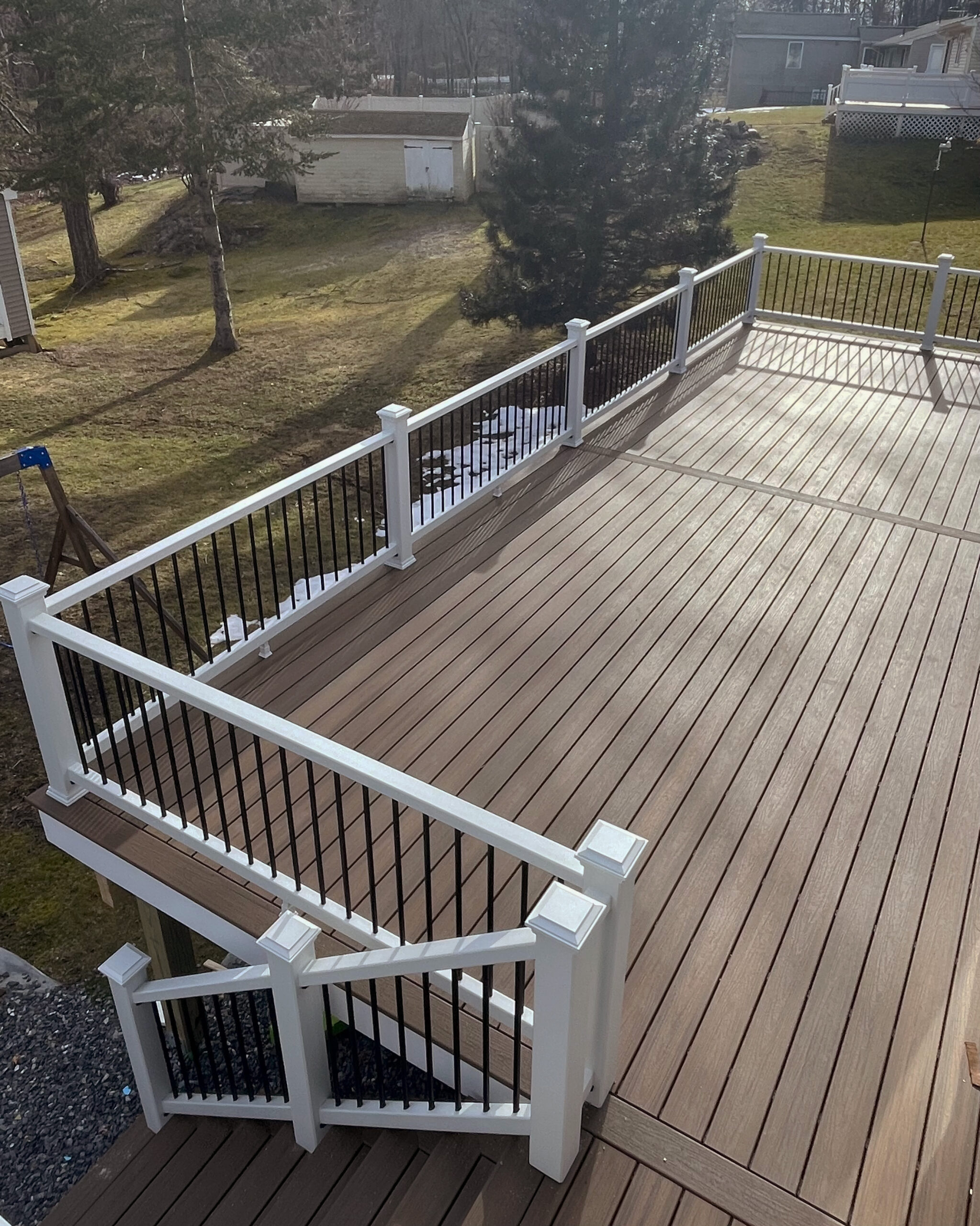 Trex composite decking in color Toasted Sand with Trex select railings in white with black balusters.