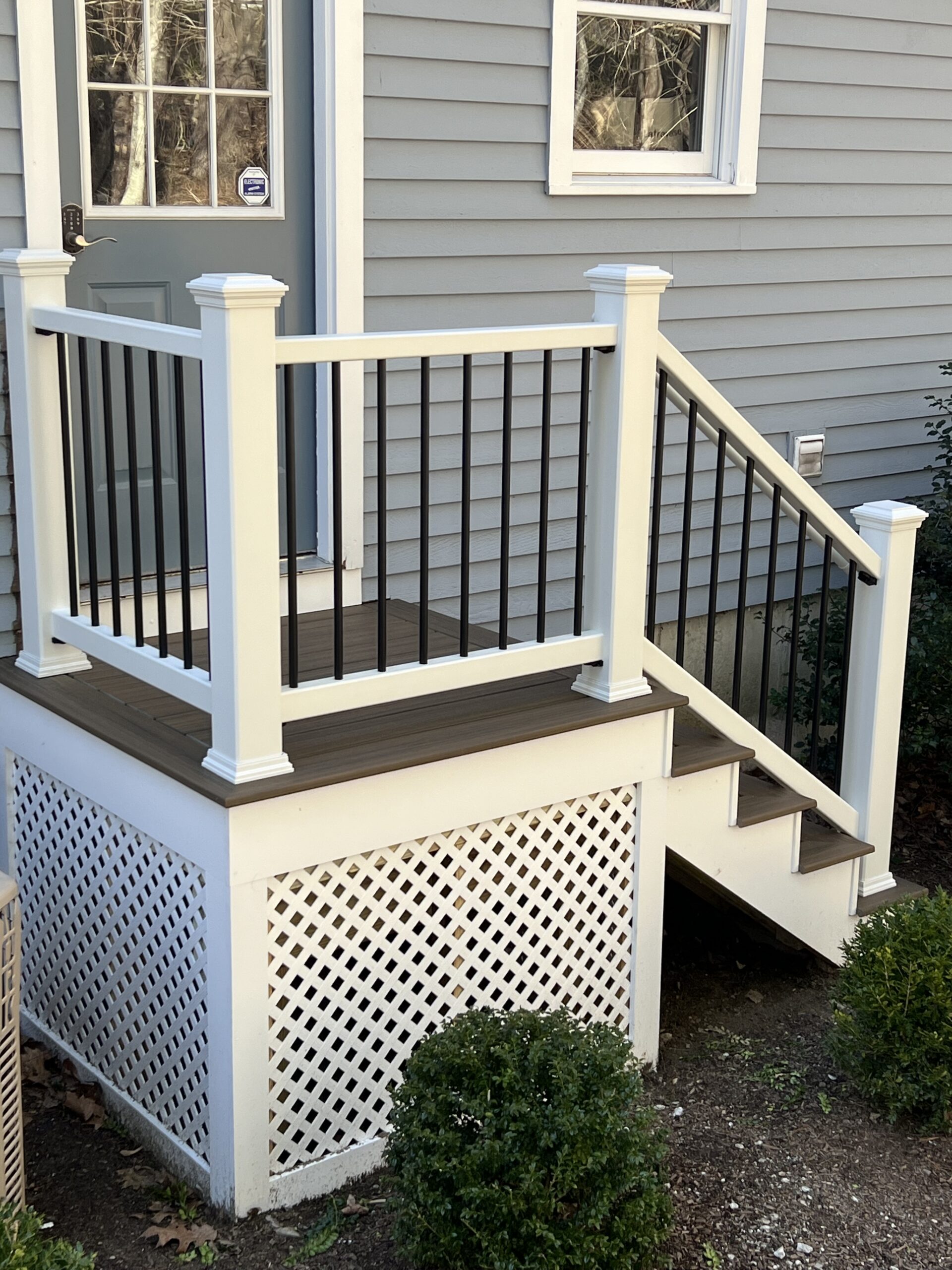 Small deck with stairs with trex toasted sand and white railings.